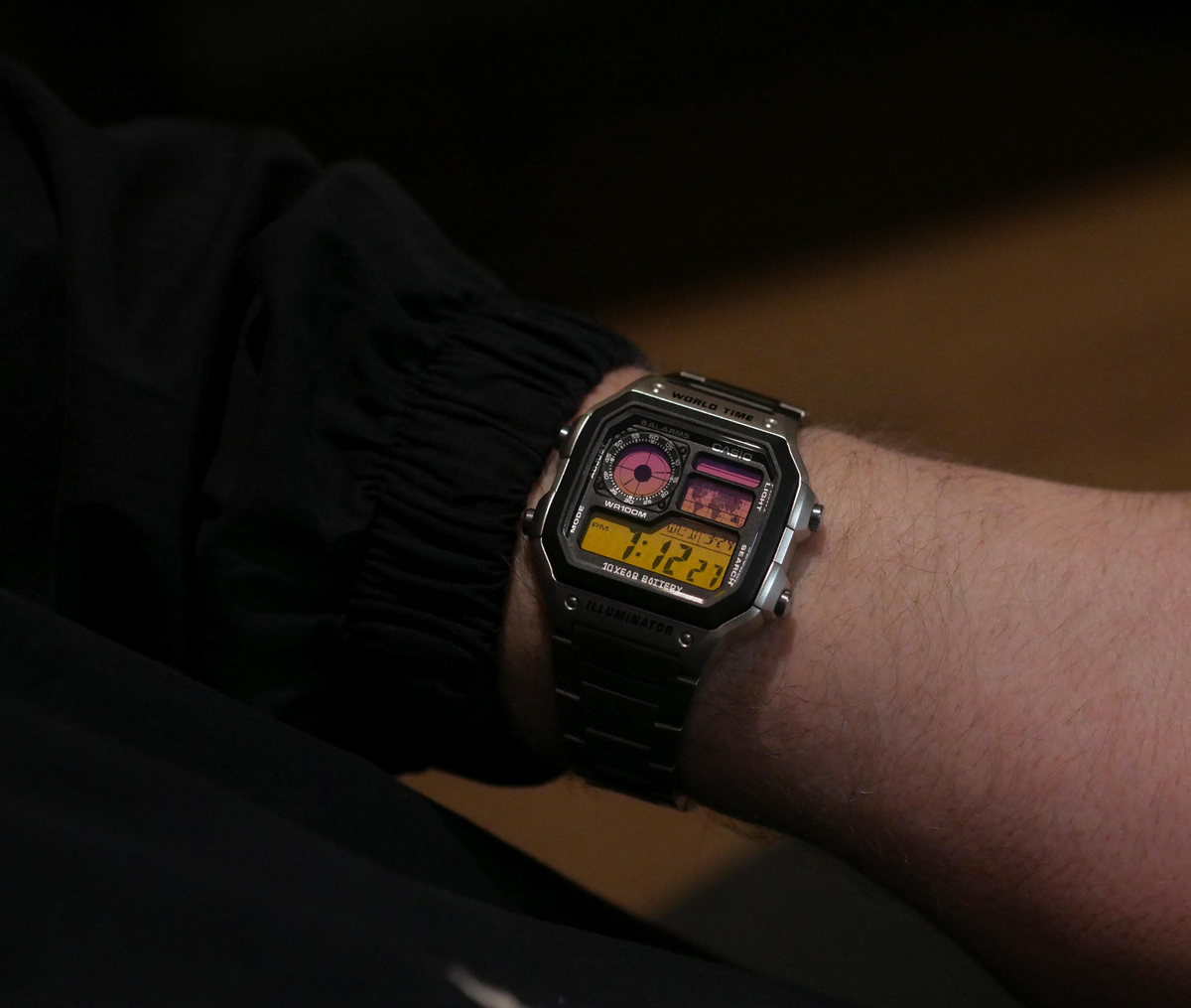 Custom Casio AE-1200 sunset-gradient watch worn on the wrist in a dark lifestyle setting
