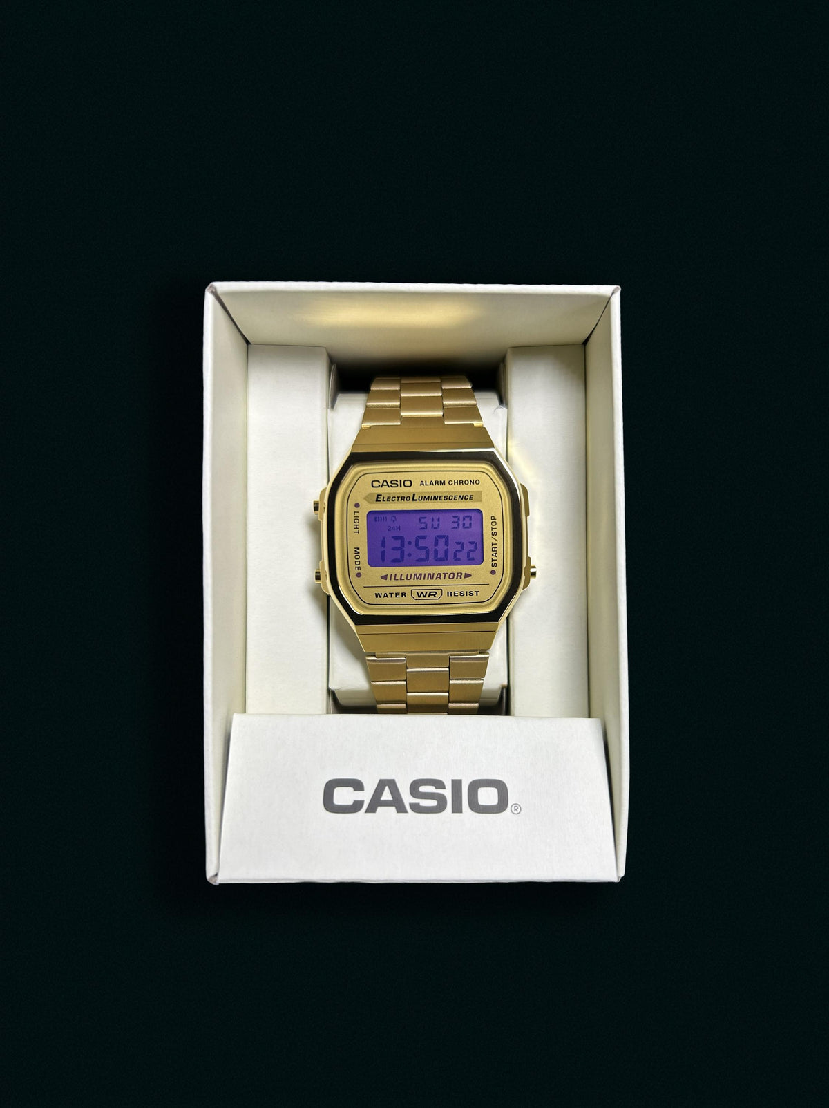 Gold-tone Casio A168 with purple display presented in its Casio box