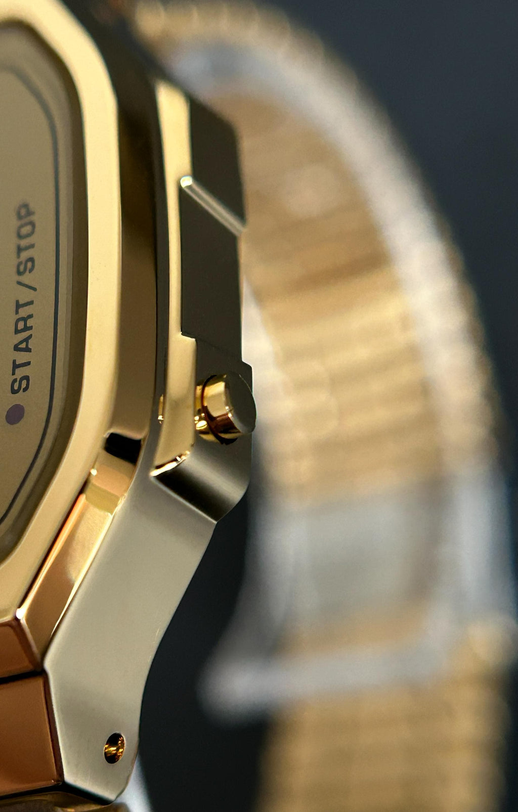 Side detail of the gold-tone Casio A168 with green display and stainless-steel bracelet