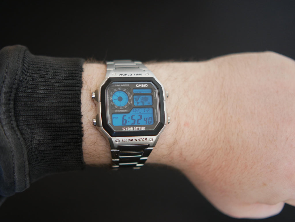 Custom Casio AE-1200 blue display watch with stainless-steel bracelet worn on a wrist